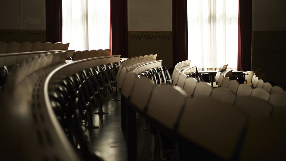 Sitzreihen und Klapptische in einem leeren Vorlesungssaal der Uni Zürich