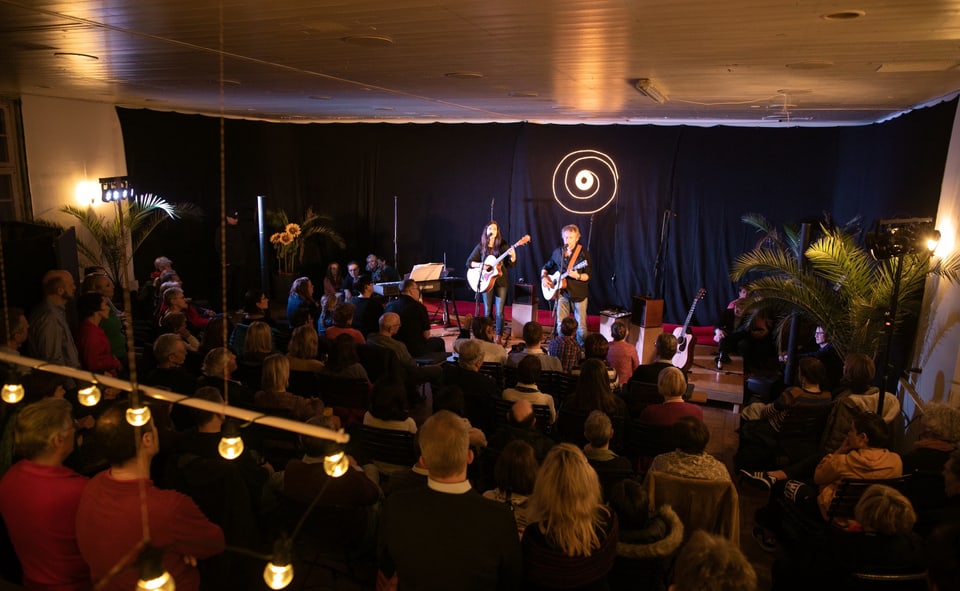 Ein Theatesaal in einer Landbeiz - Publikum im Saal, zwei Künstler mit Gitarre auf der Bühne.