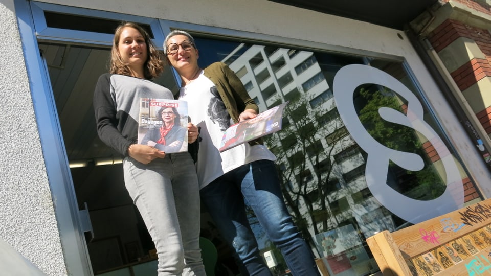 Blick von unten auf zwei Frauen mit je einem Surprise-Heft in der Hand