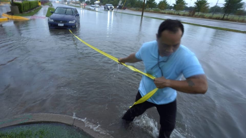 Mann zieht Auto durch das Hochwasser.