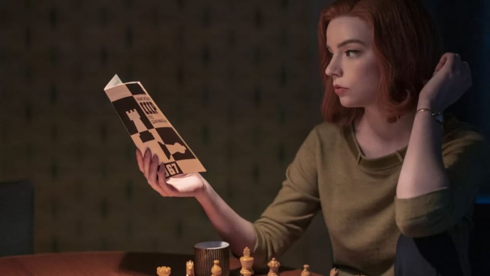 Eine Schachspielerin studiert ein Fachbuch.