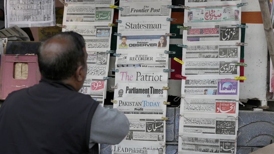 Ein Mann steht vor einer Zeitungsauslage