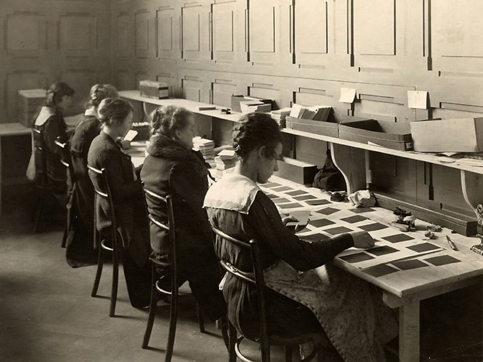 Mehrere Frauen sitzen an einem langen Tisch und bearbeiten Karteikarten.