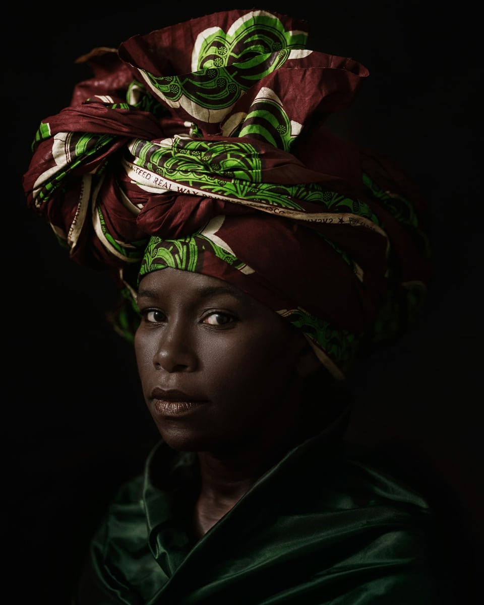 Porträt einer jungen schwarze Frau mit buntem Tuch auf dem Kopf.