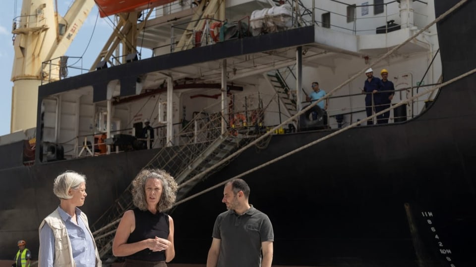 zwei Frauen und ein Mann vor einem Schiff.