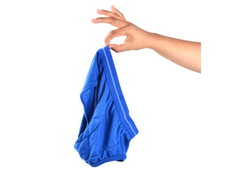 Eine Frau hält mit zwei Fingern eine blaue Unterhose.