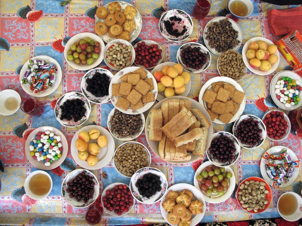 Auf einem Tisch stehen etwa dreissig Schalen mit verschiedenen Früchten, Gebäck und Süssigkeiten.