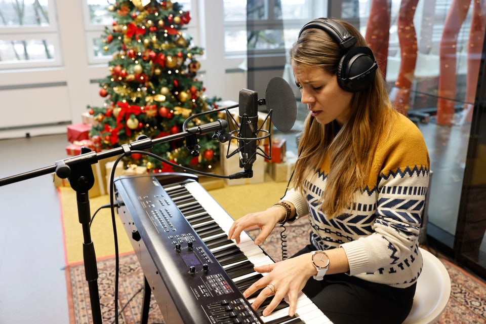 Junge Frau am E-Piano, im Hintergrund ein Weihnachtsbaum