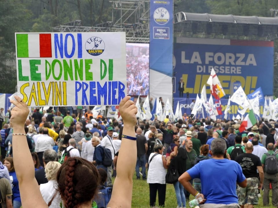 Salvinis Anhänger halten Transparente hoch und stehen vor der Rednerbühne.