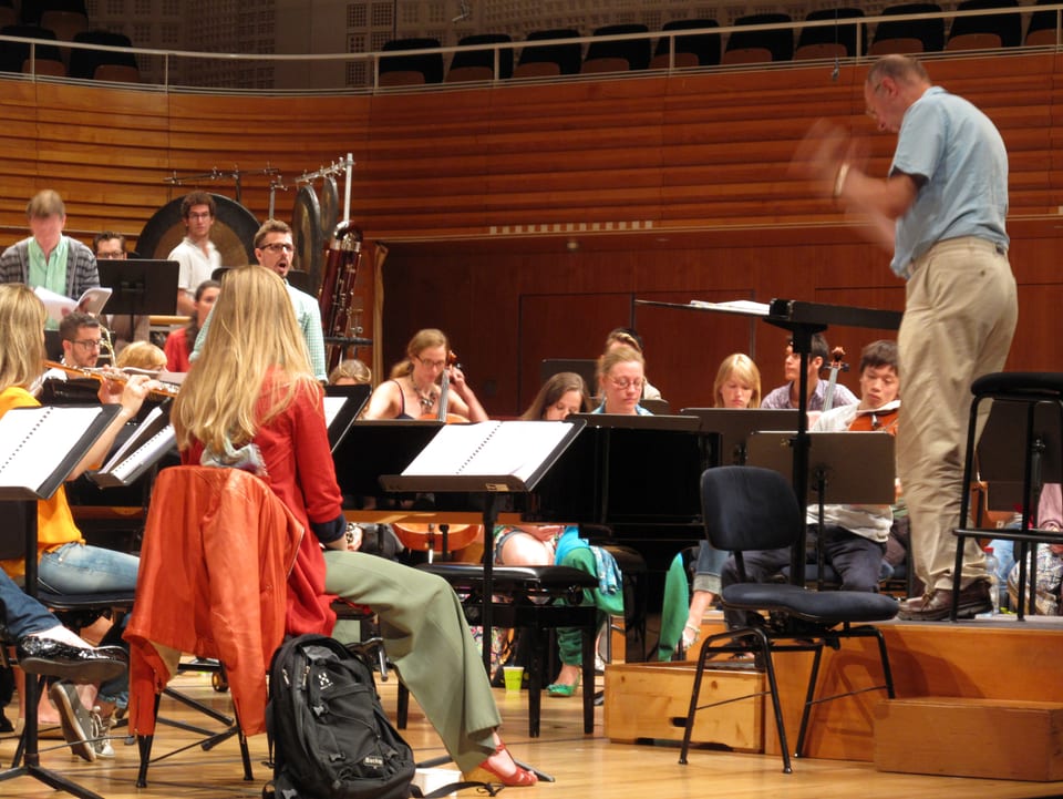 James Wood am Dirigentenpult, konzentrierte Musikerinnen und Musiker  der Festival Academy.