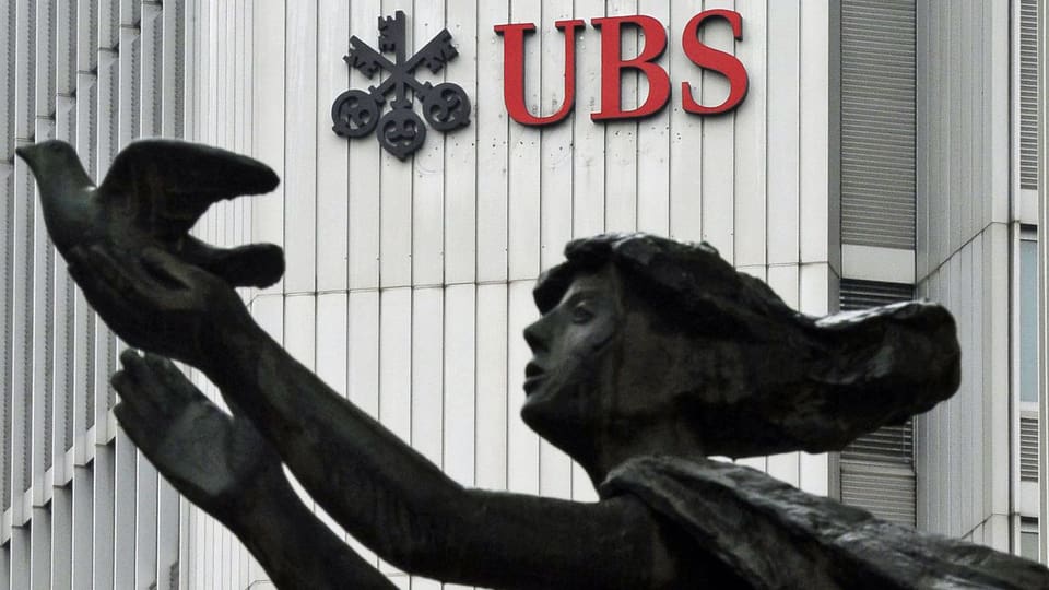 Der Schriftzug der Schweizer Grossbank UBS in Zürich. Im Vordergrund eine Frauenskulptur mit einer Taube. (keystone) 
