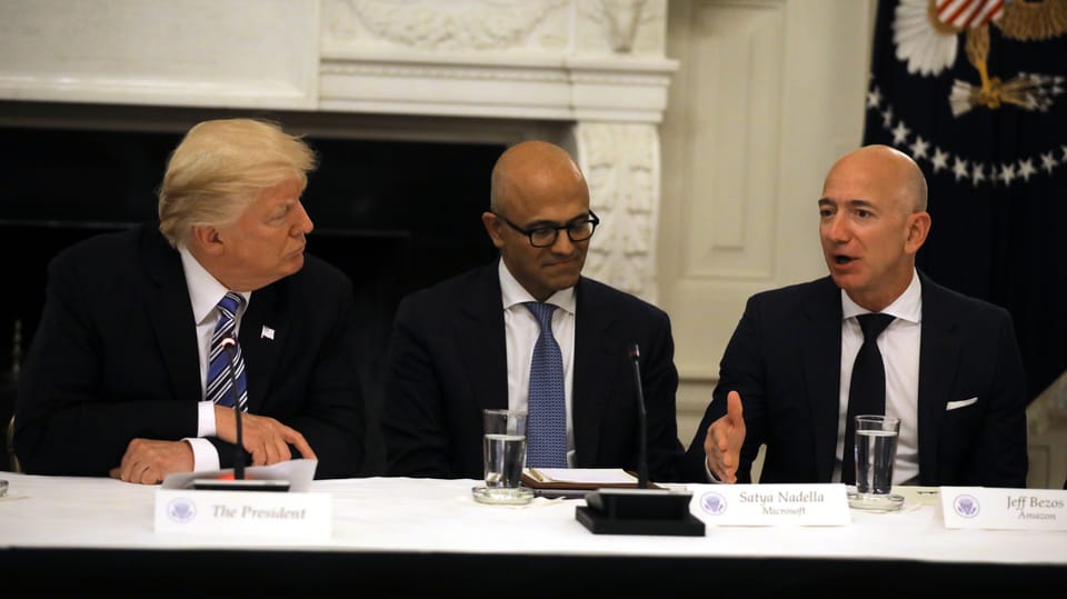 Trump, Nadella und Bezos sitzen nebeneinander.