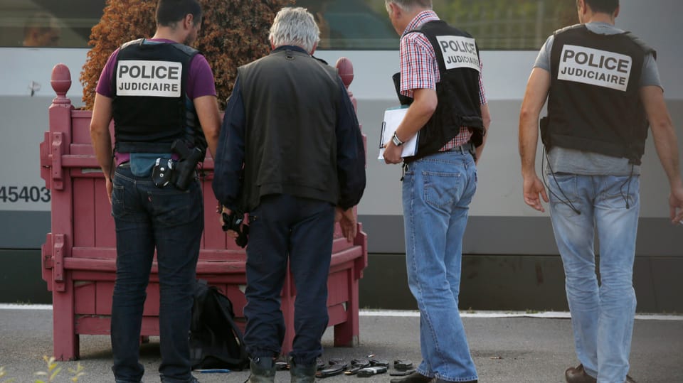 Französische Polizisten stehen auf einer Plattform und schauen sich Beweismaterial an