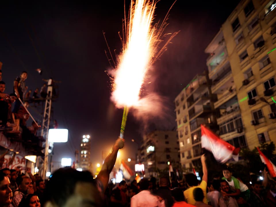 Ein Mann entzündet Feuerwerk in einer Menschenmenge.