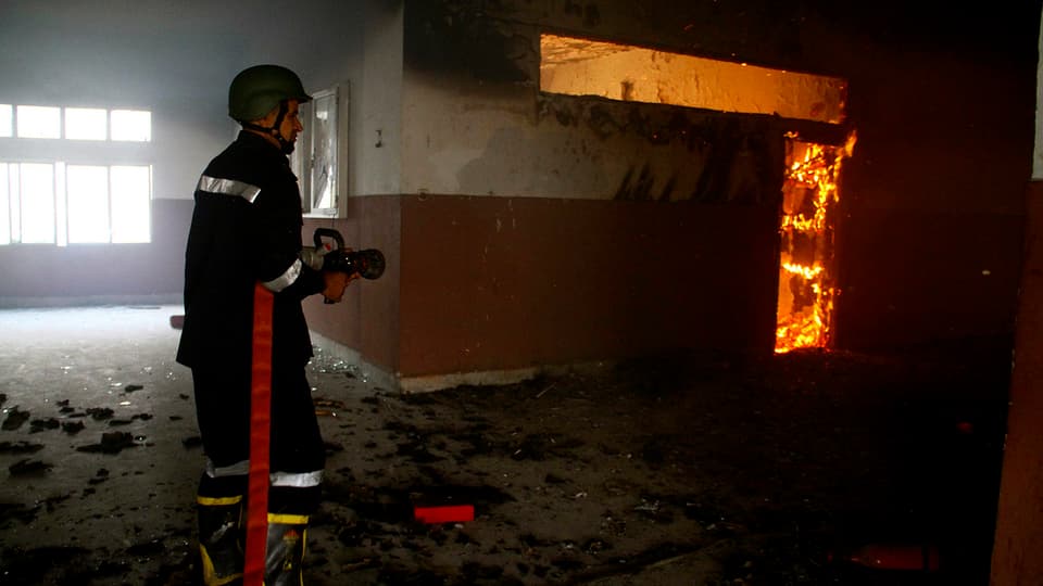 Ein Feuerwehrmann löscht ein Feuer innerhalb des verwüsteten Uni-Gebäudes.