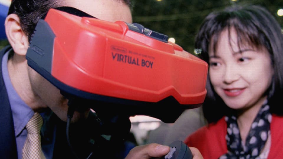 Ein Mann trägt eine rote VR-Brille mit der Aufschrift Virtual Boy.