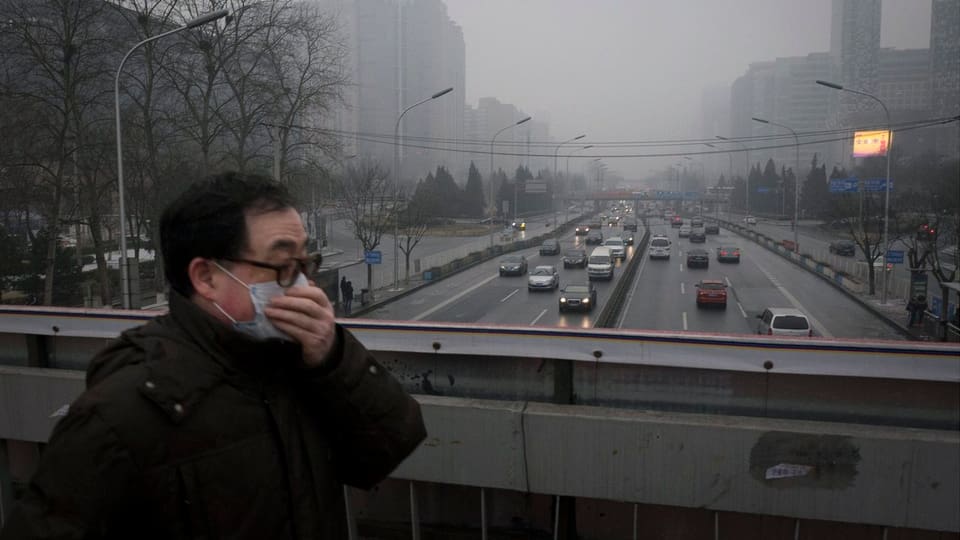 Ein Mann mit Mundschutz hastet über eine Brücke in Peking.
