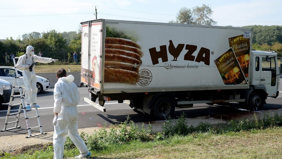 Zwei Forensiker stehen neben einem geparkten Lastwagen auf dem Pannenstreifen einer Autobahn.
