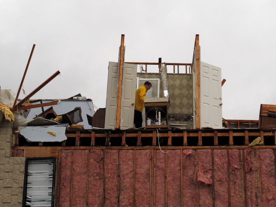 Ein Mann besichtigt die Trümmer eines Hauses.