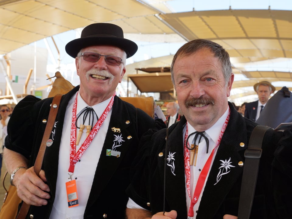 Zwei Alphornisten in Trachtenoutfit mit Badge-Zugang zur Expo um den Hals.