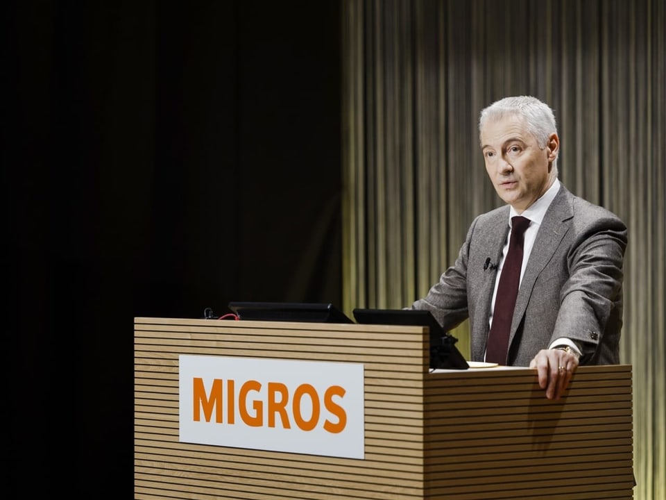Fabrice Zumbrunnen steht an einem Rednerpult, auf dem das Logo der Migros prangt.