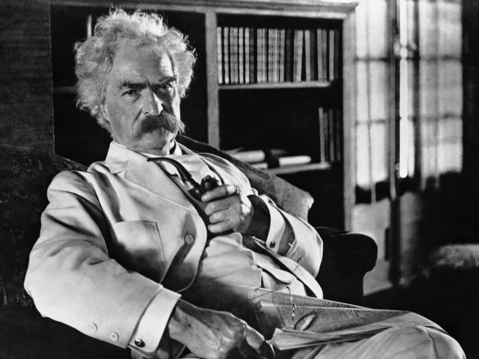 Historical photo: Mark Twain with a pipe in his chair.
