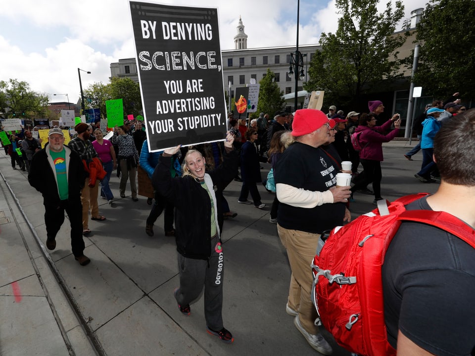 Eine Frau hält ein Plakat, auf dem steht: «Mit dem Leugnen der Wissenschaft, machst du Werbung für deine Dummheit».