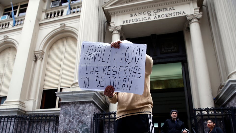 Ein Mann steht vor der argentinischen Zentralbank mit einem Transparent. Darauf steht: «Vanoli, hör zu: Die Reserven werden nicht angefasst!»
