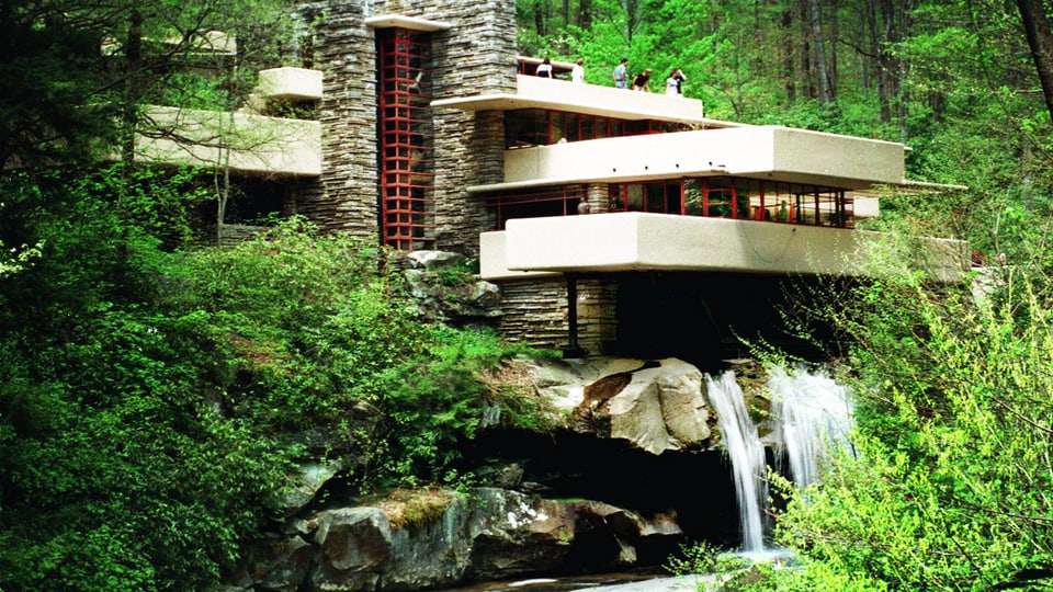Ein Haus steht im Wald auf einem Wasserfall.