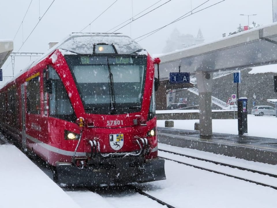 Red train at railway station with a lot of snow
