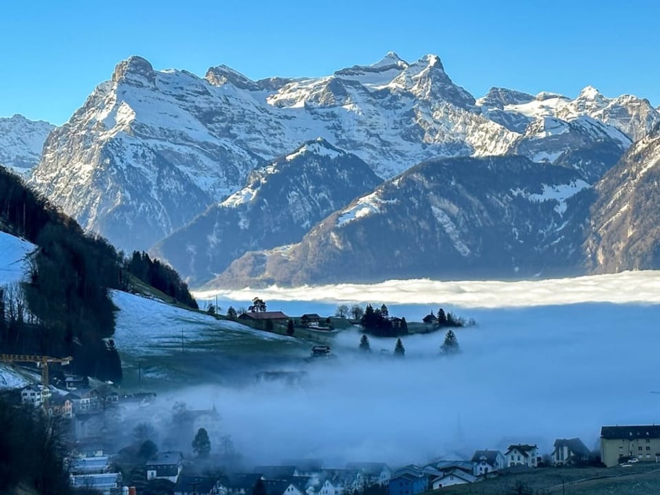 Nebel über dem See, darüber Alpen und blauer Himmel.