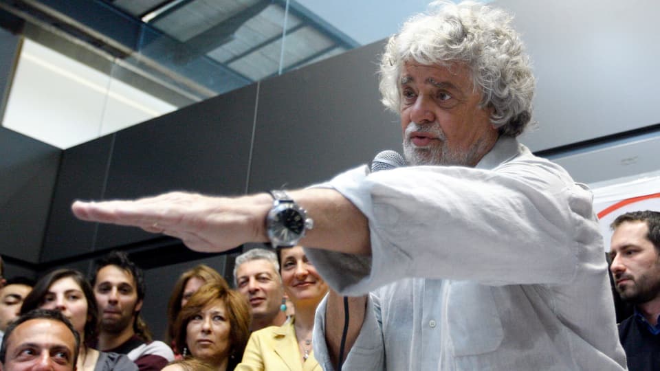 Grillo gestikuliert bei einer Medienkonferenz im April 2013, im Hintergrund Zuschauer.