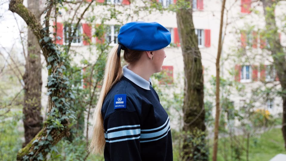 Eine Frau in Securitas-Uniform vor einem Wohnhaus. 