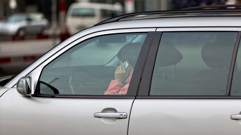Eine Frau telefoniert mit ihrem Handy am Steuer ihres Autos.