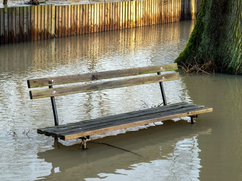 Eine Parkbank ist fast unter Wasser.