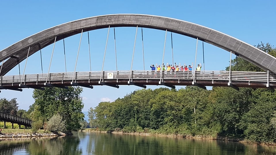 Winkende Menschen auf einer Brücke.
