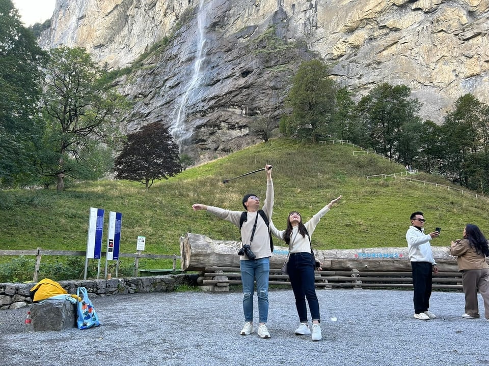 Leute fotografieren sich selbst vor Wasserfall