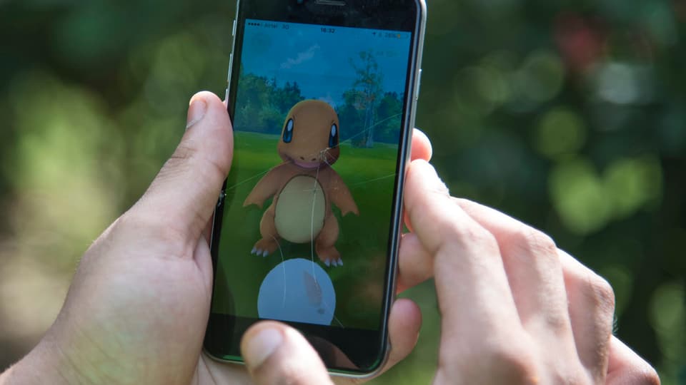 Grossaufnahme eines Handys mit Pokémon auf dem Display, von einem Spieler gehalten