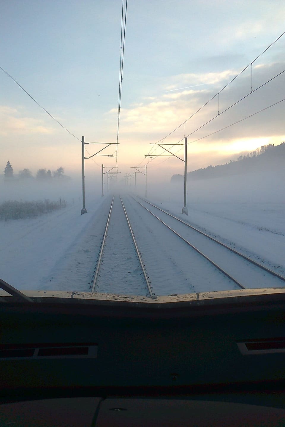 Sicht aus dem Führerstand auf die winterlich-verschneiten Bahnschienen.