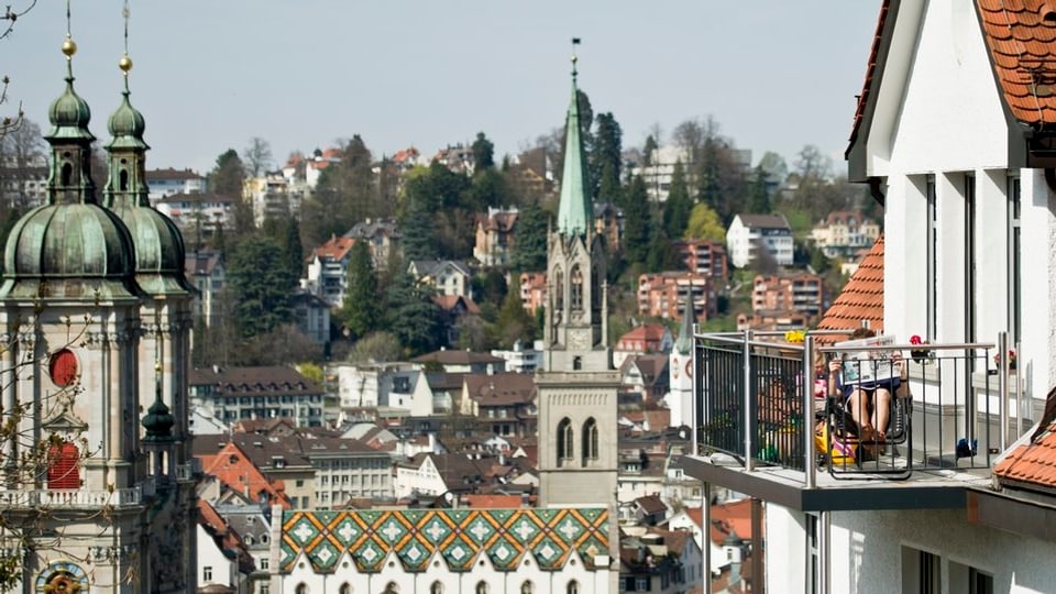 Ein Mann liest auf einem Balkon in der Stadt St. Gallen.