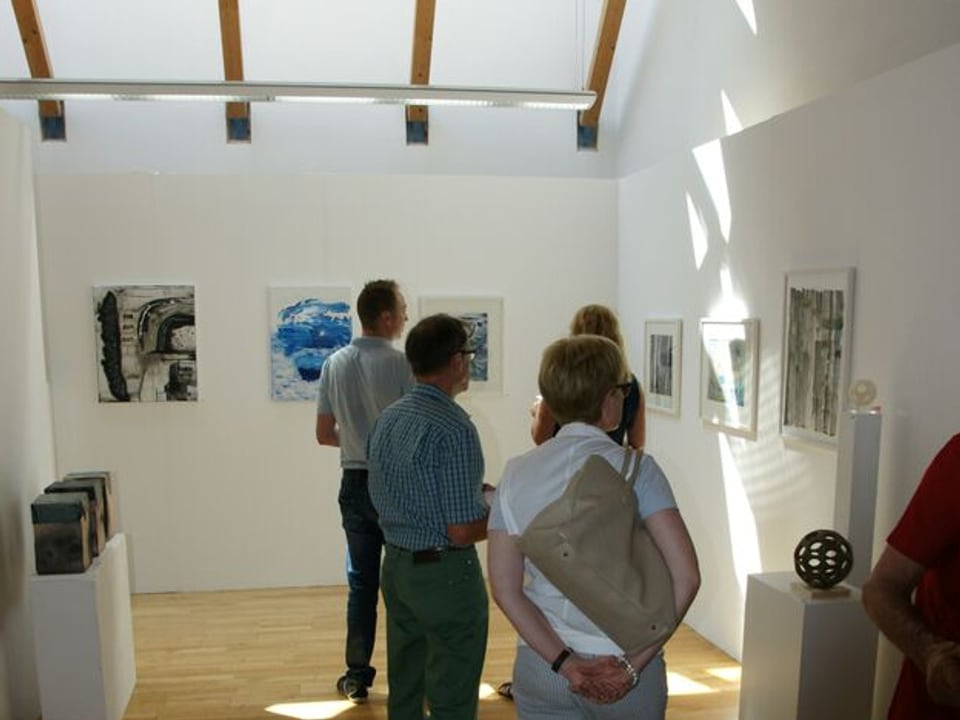 Lustwandelnde Besucher betrachten Gemälde und Skulpturen.