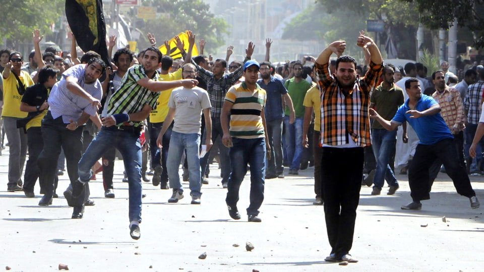 Anhänger der Muslimbrüder demonstrieren in einer Strasse in Kairo. Einige werfen mit Steinen.