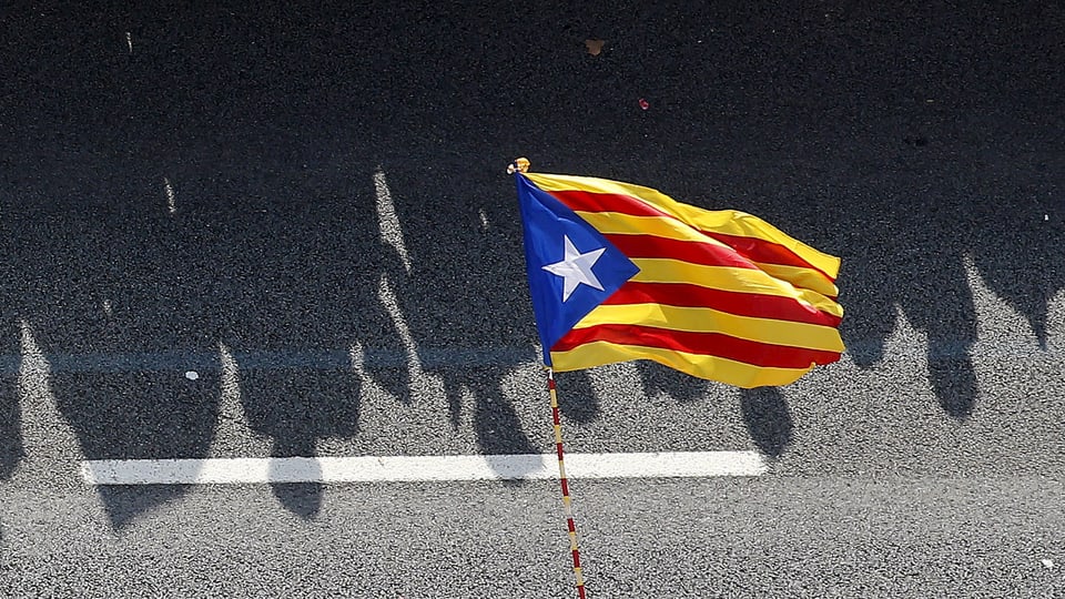 Menschenschatten hinter der Flagge Kataloniens