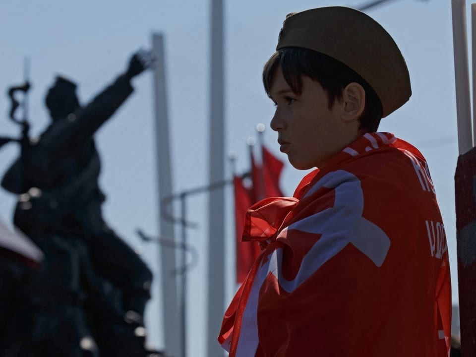 Ein Junge, der die sowjetische Flagge trägt, beobachte eine Parade des Sieges in Wladiwostok.