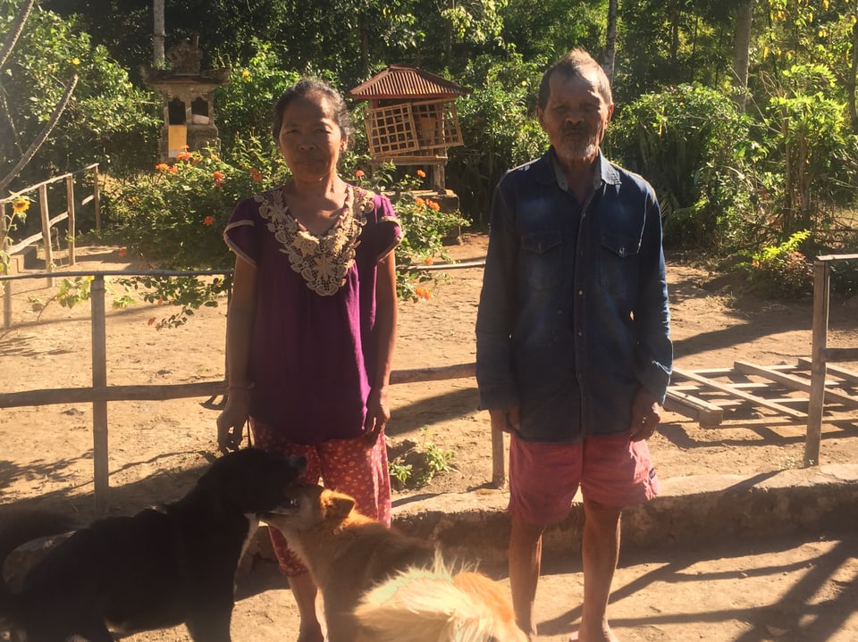 Ein älteres Pärchen mit zwei Hunden auf ihrem Land in Bali.