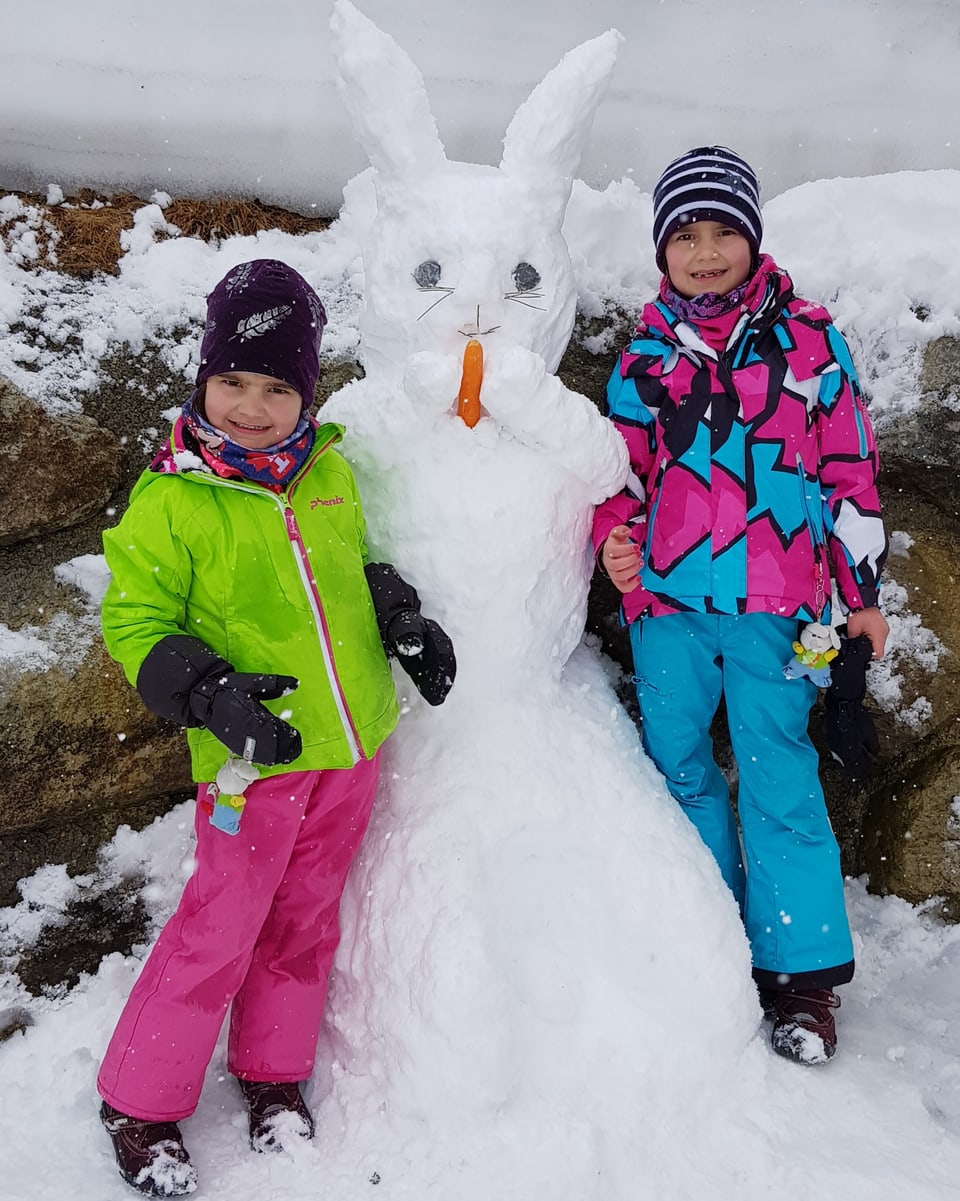 Zwei Kinder und ein Osterhase aus Schnee.
