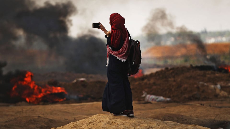 Eine Frau filmt in Gaza am 14. Mai brennende Reifen.