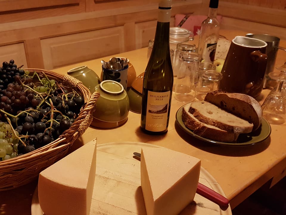 Trauben, Käse, Wein und Brot auf einem Tisch.