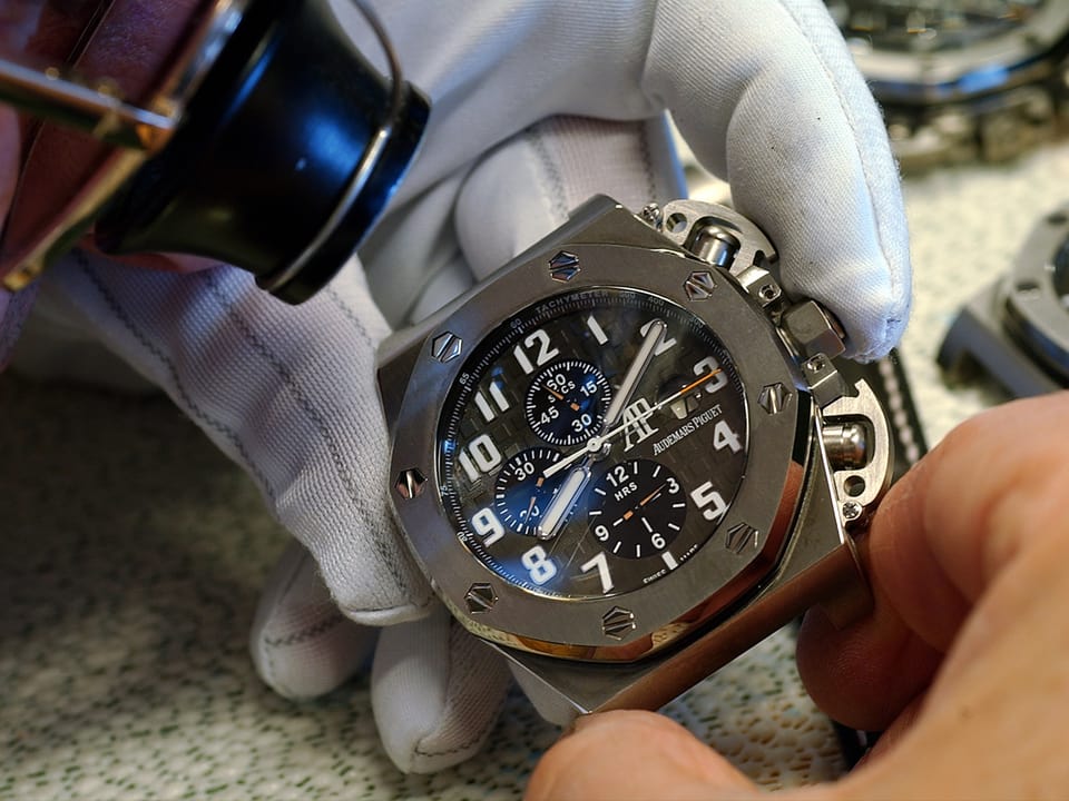 Ein Uhrmacher hält eine Uhr in Händen.