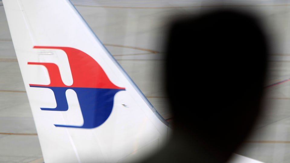 Silhouette eines Kopfes vor einem Flugzeug der Malaysian Airlines